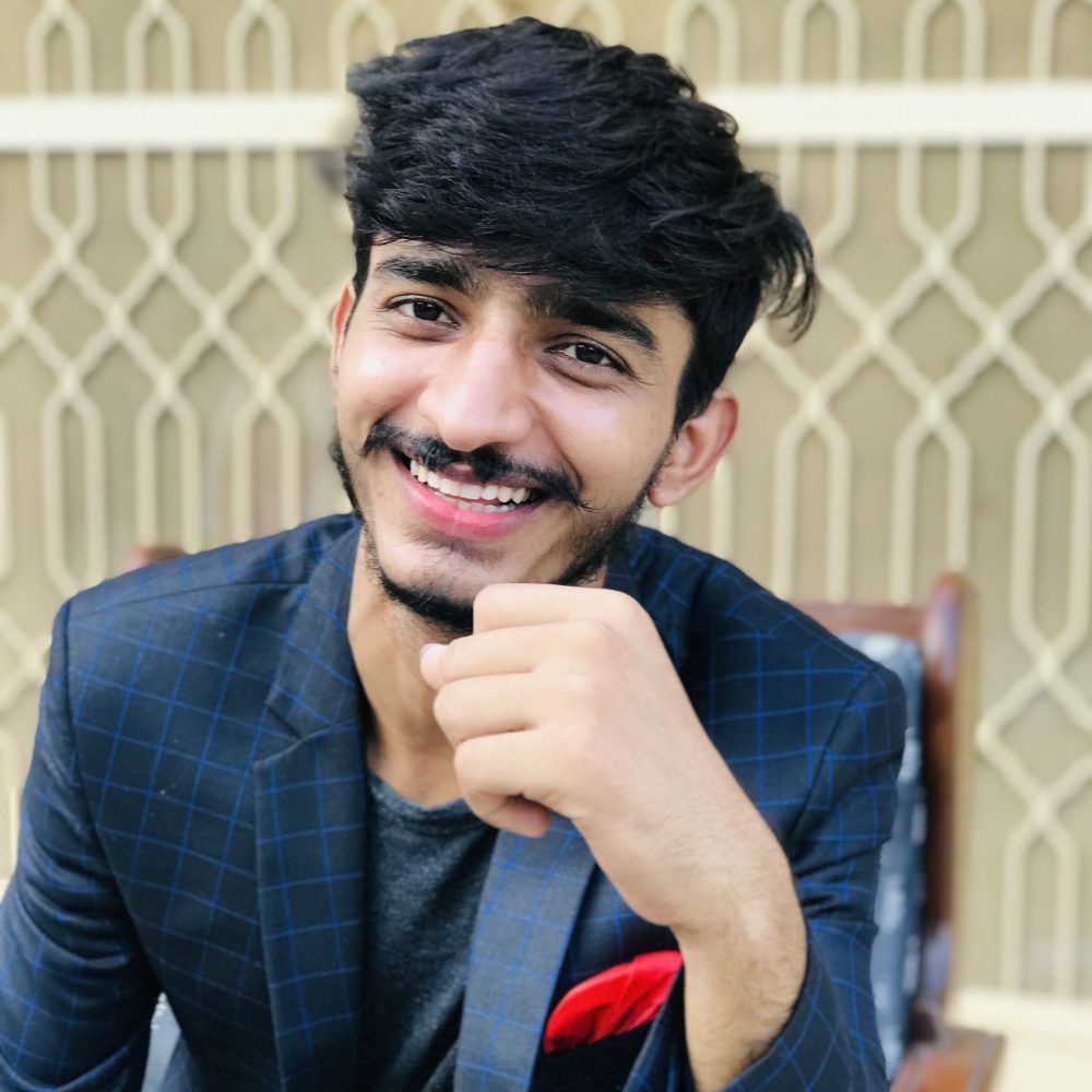 portrait-young-man-standing-against-fence